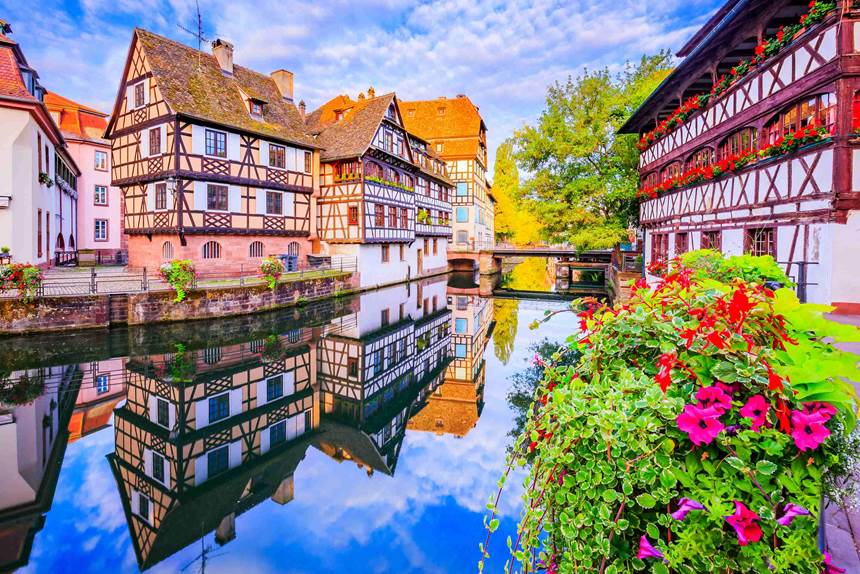 Charming European village with colorful half-timbered houses reflected in a serene canal.