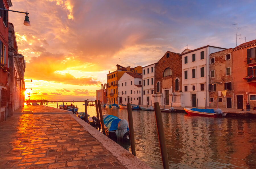 Grand sunset over the Cannaregio canal in Venice, Italy, with vibrant colors reflecting on the water's surface.