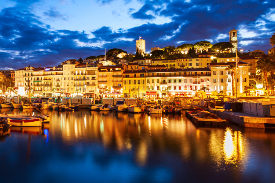 Aerial panoramic view of Cannes at night, showcasing the city lights and vibrant atmosphere along the coastline