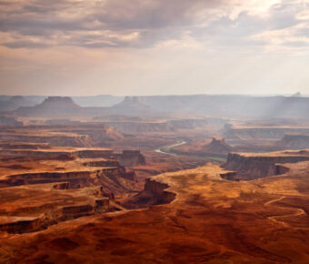 Expansive view of Canyonlands National Park in Utah, showcasing rugged canyons and colorful rock formations under a clear sky.