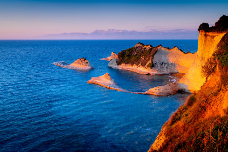 Sunset over Cape Drastis rock formations in Corfu, showcasing the stunning Greek coastline and popular viewpoint.
