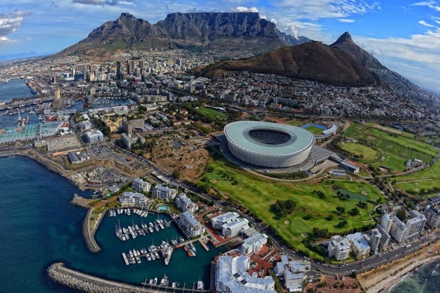 Aerial view of Cape Town with stadium, harbor, and Table Mountain backdrop.