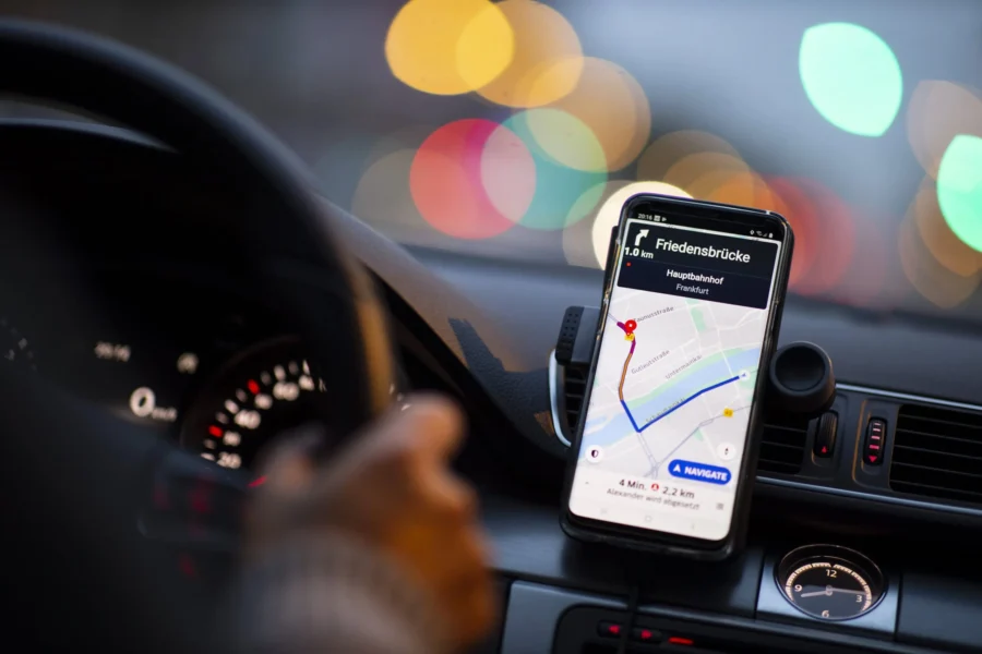 Car smartphone navigation showing route to Friedensbrücke Hauptbahnhof Frankfurt at night.