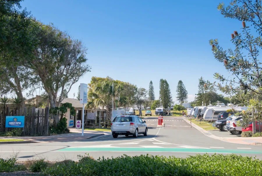 Coolum Beach Holiday Park entrance with boom gate, caravans, family campground and sunny blue sky.