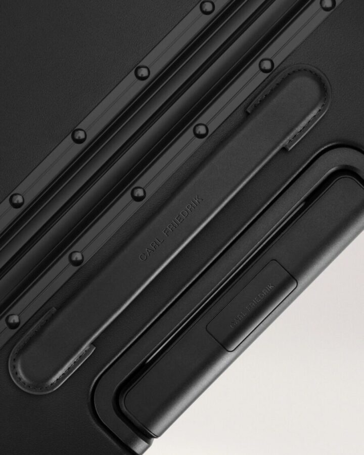 Close-up of the black handle on a Carl Friedrik Carry-on X suitcase, showcasing its sleek design and sturdy grip.