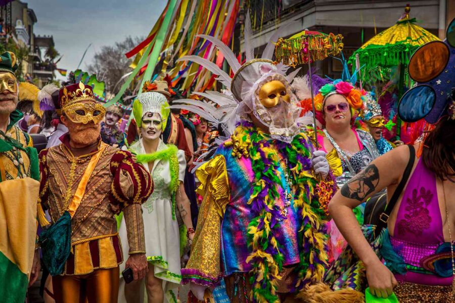 Festive parade with vibrant costumes, masks, and historic backdrop celebrating culture and community.