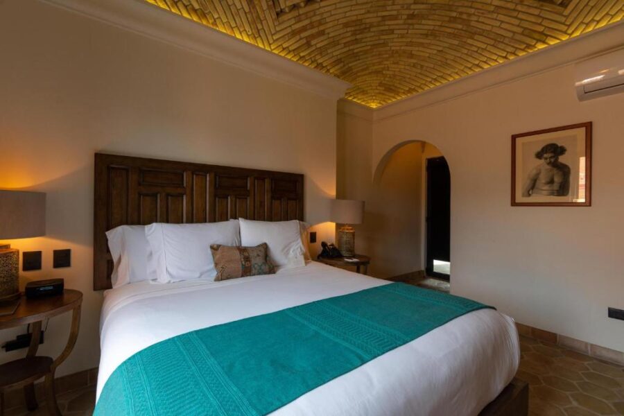 Stylish bedroom showcasing a large bed and a ceiling adorned with brick walls at Casa 1810 Parque Hotel Boutique.

