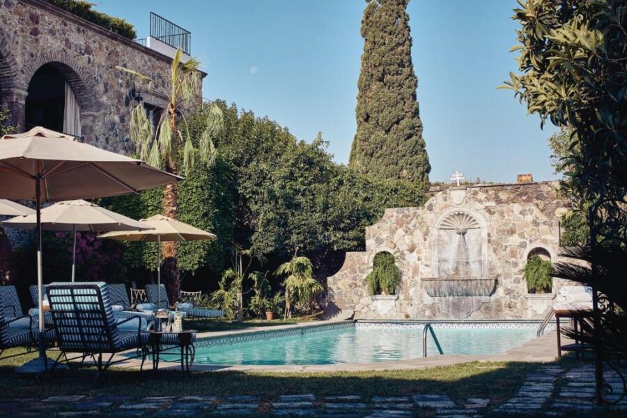 Poolside view featuring chairs and umbrellas at Casa de Sierra Nevada, A Belmond Hotel, in San Miguel de Allende.
