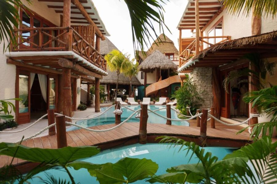 Casa Las Tortugas Petit Beach Hotel & Spa showcases a tranquil pool area with a wooden walkway leading through lush surroundings.
