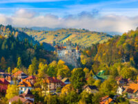 Autumn panorama of Bran Castle, a popular tourist site in Transylvania, surrounded by vibrant fall colors and scenic hills.