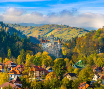 Autumn panorama of Bran Castle, a popular tourist site in Transylvania, surrounded by vibrant fall colors and scenic hills.