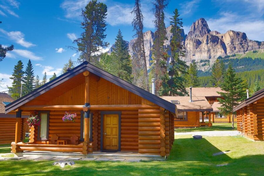 Log cabins set against a mountainous backdrop at Castle Mountain Chalets, Canada, showcasing a serene retreat.