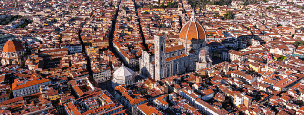 Aerial view of the Cathedral of Santa Maria del Fiore in Florence, showcasing its iconic red-tiled dome and surrounding architecture