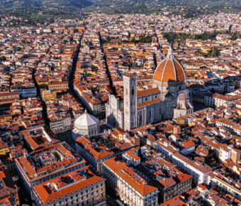 Aerial view of the Cathedral of Santa Maria del Fiore in Florence, showcasing its iconic red-tiled dome and surrounding architecture