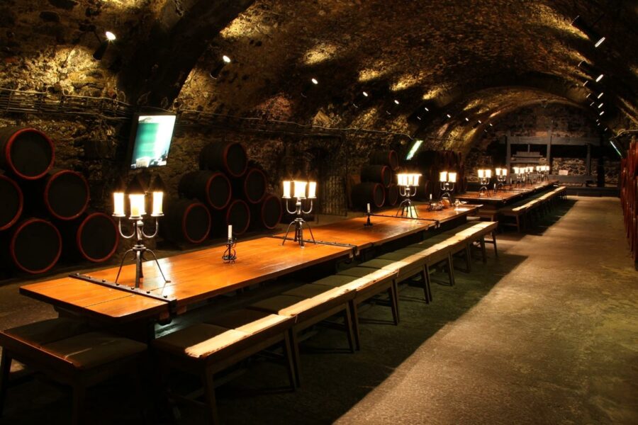 Rákóczi wine cellar banquet hall with stone vaults, wooden tables, and stacked barrels.