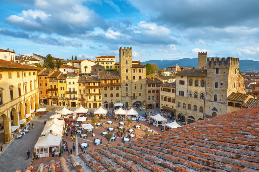 Central square of Arezzo, Italy, bustling with activity showcasing local vendors and visitors