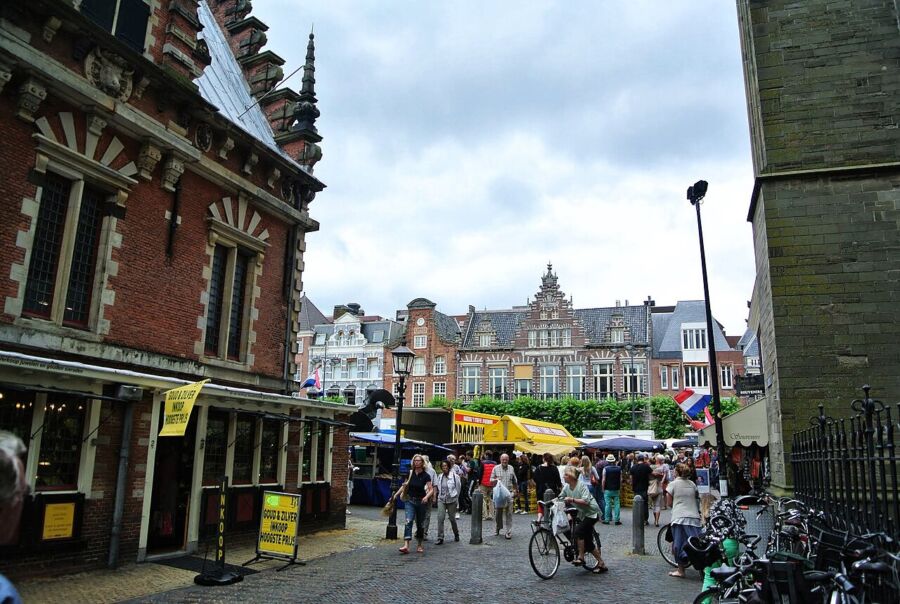People walk together on a cobblestone street in Haarlem's city center, showcasing the area's charming architecture.
