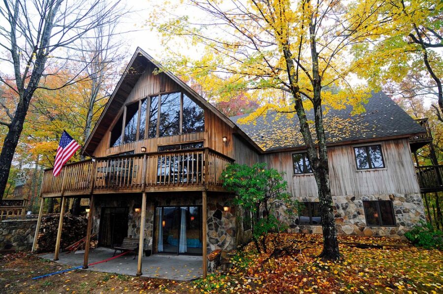 Cozy log cabin surrounded by autumn foliage in Chalet Village, Gatlinburg, highlighting the beauty of fall.