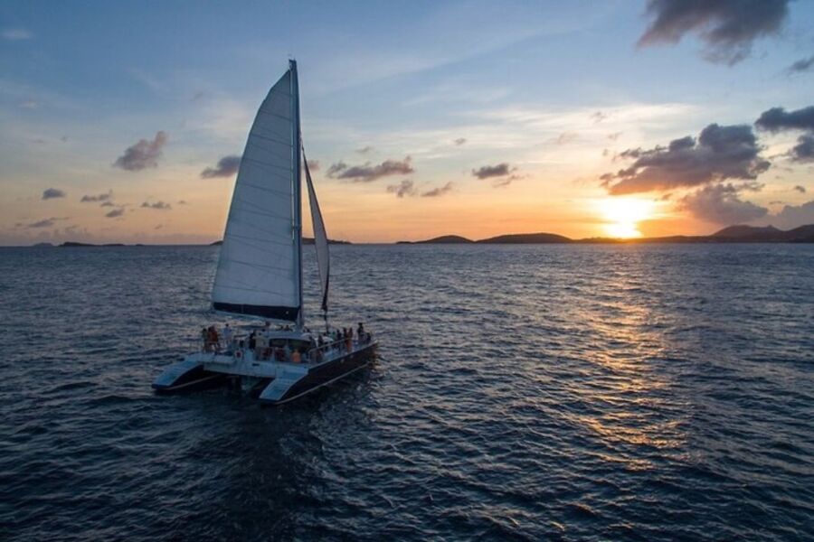 Catamaran sails on the ocean at sunset, part of the Champagne Sunset Sail experience from Cruz Bay.