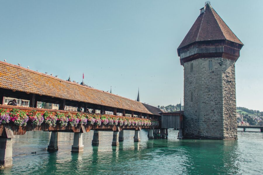 Lucernes Chapel Bridge and Water Tower, iconic landmarks with flowers and lake reflection.