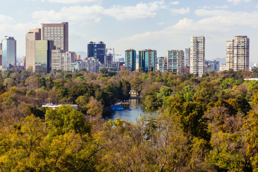 Panoramic view of Mexico City's skyline featuring Lake Chapultepec, showcasing urban architecture and greenery
