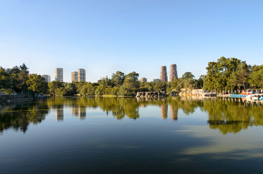 Panoramic view of a lake in Chapultepec Park, framed by the modern skyscrapers of Mexico City's skyline