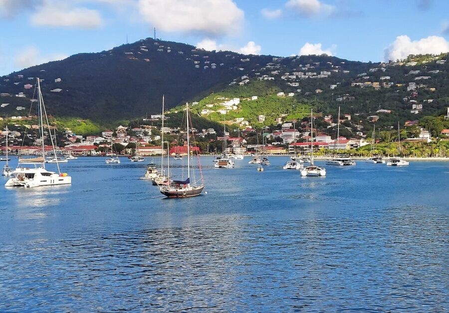 Scenic bay in Charlotte Amalie, St. Thomas, filled with boats and framed by a lush green hill in the background.