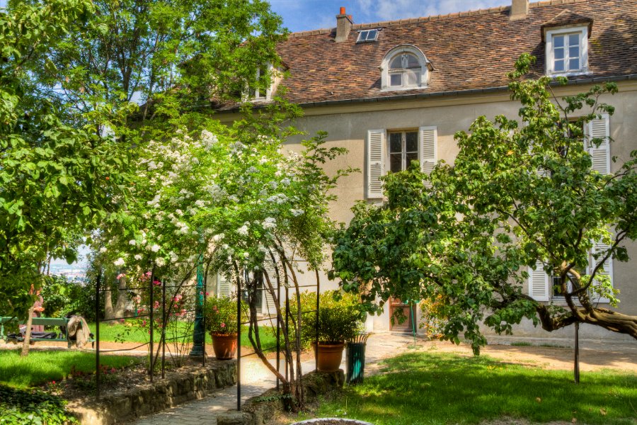 Musée de Montmartre sunlit courtyard garden with terracotta roof historic house in Paris.