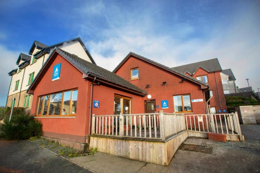 Quaint hostel with rustic architecture surrounded by nature in a scenic, welcoming setting.