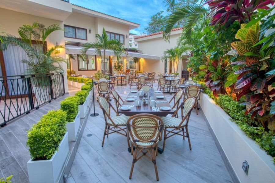 Elegant tropical outdoor dining area with lush greenery and cozy ambiance at sunset.