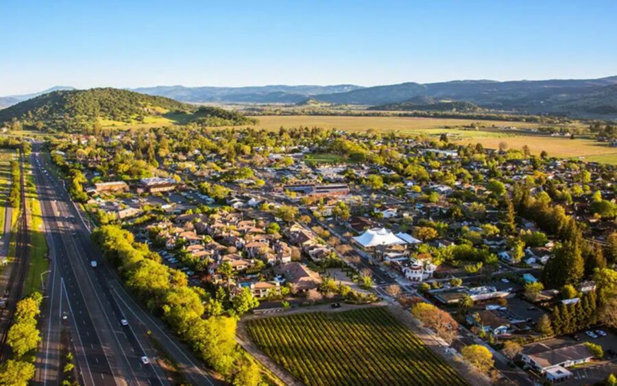 Aerial view of Yountville: picturesque town, rolling hills, vineyards, vibrant community.