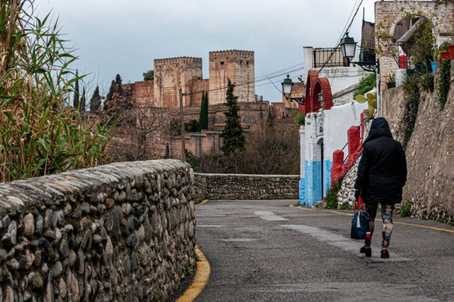Charming historic street with vibrant houses, stone walls, and majestic fortress background.