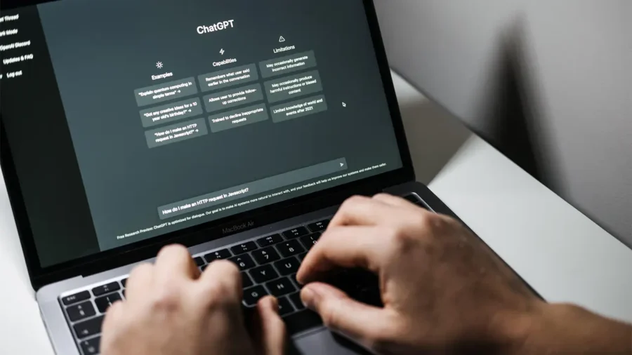 Person typing on laptop running ChatGPT interface for JavaScript HTTP request programming help.