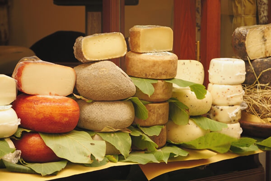 Artisanal cheese display with red apples, green leaves, and diverse cheese textures and colors.