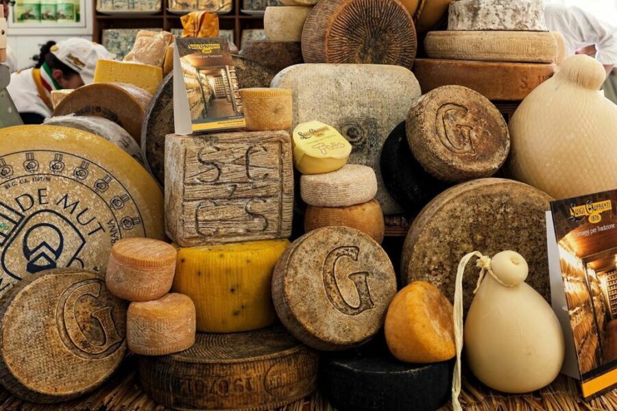 Artisanal cheese display at vibrant market, featuring diverse types and rich textures.