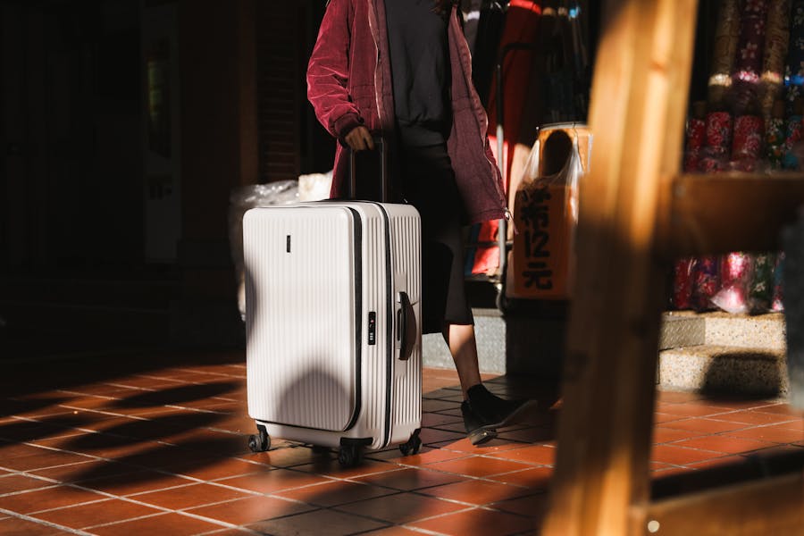 Traveler in lively market with chic suitcase and casual attire.