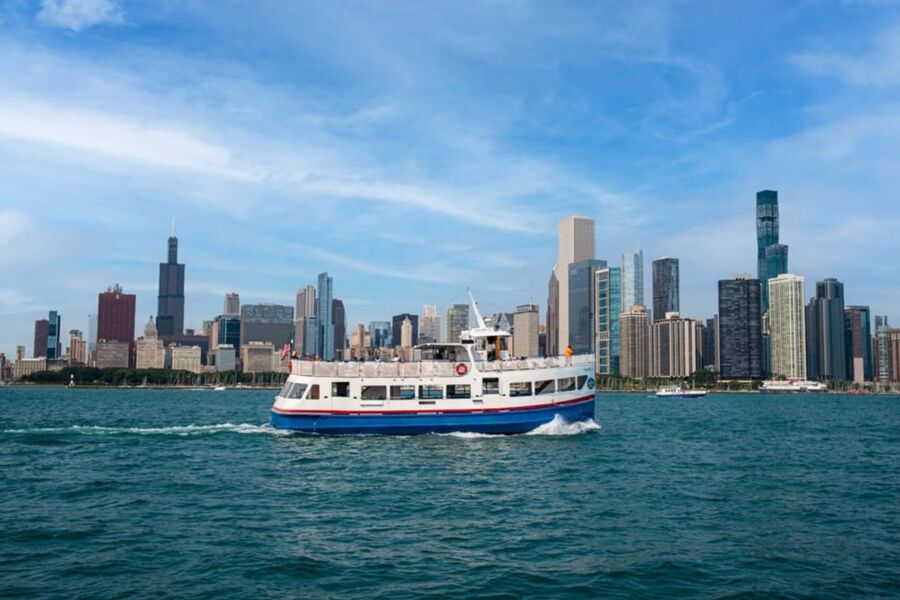 Chicago city skyline with boat on Lake Michigan under a clear blue sky.