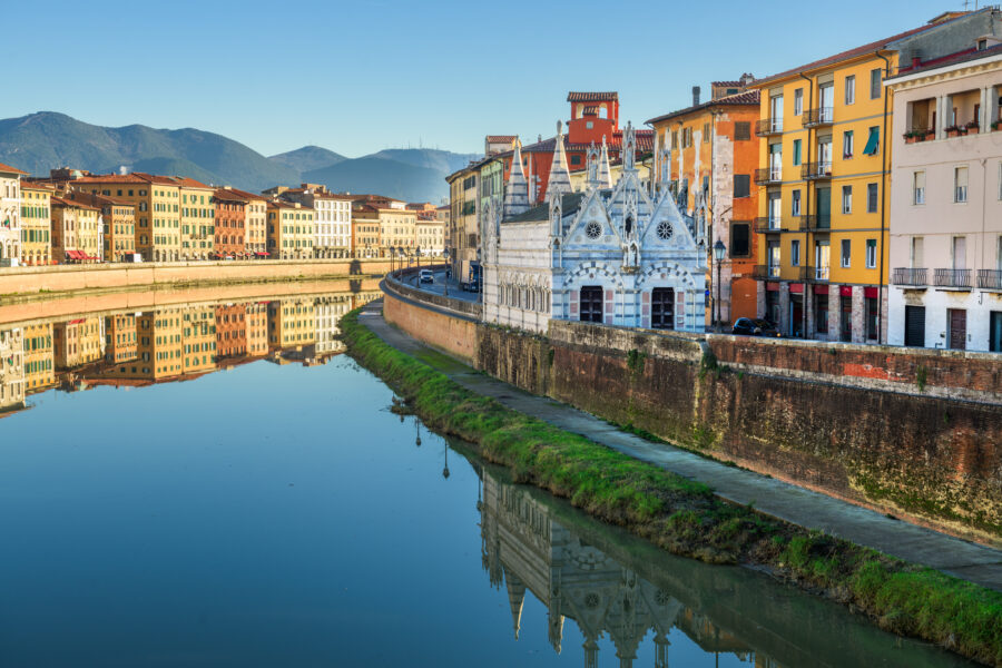 Skyline of Pisa, Italy, featuring the Arno River and the ornate Chiesa di Santa Maria della Spina along its banks