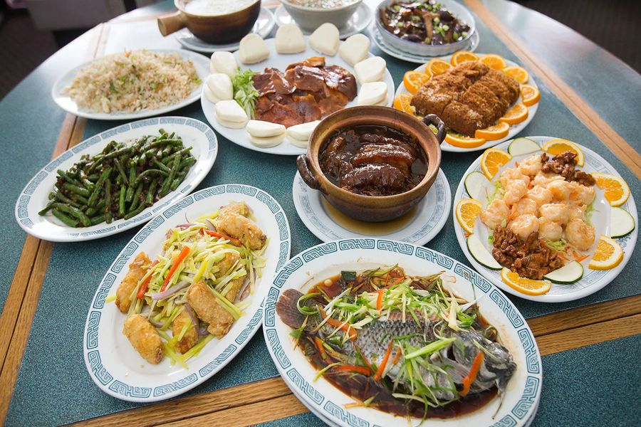 Lavish Chinese cuisine spread with fish, shrimp, stir-fried vegetables, and rice on a teal table.