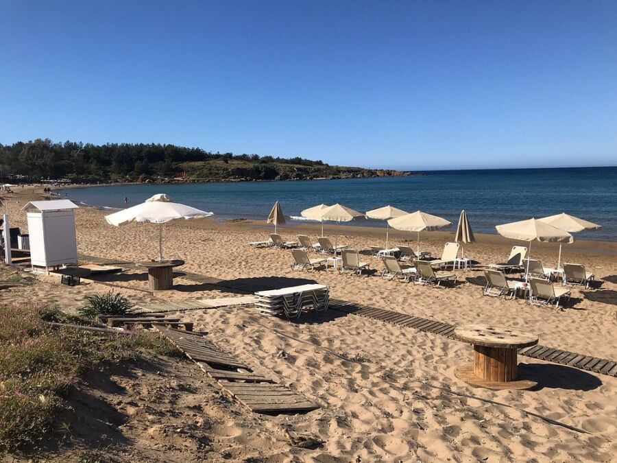 Relaxing beach view at Chrissi Akti, Paros, Greece, showcasing umbrellas and chairs arranged on the sandy shore.