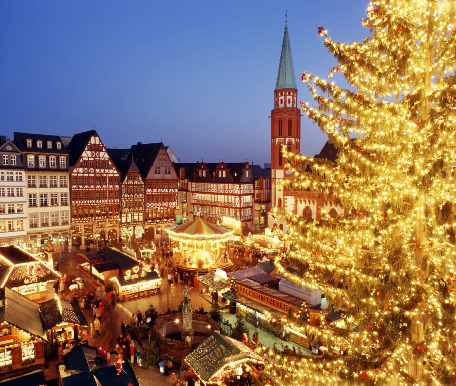 Frankfurt Christmas Market at night with illuminated tree, historic half-timbered buildings, bustling stalls.