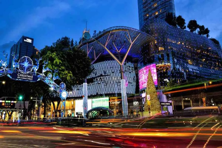 Twilight urban scene with festive Christmas lights and bustling shopping district ambiance.