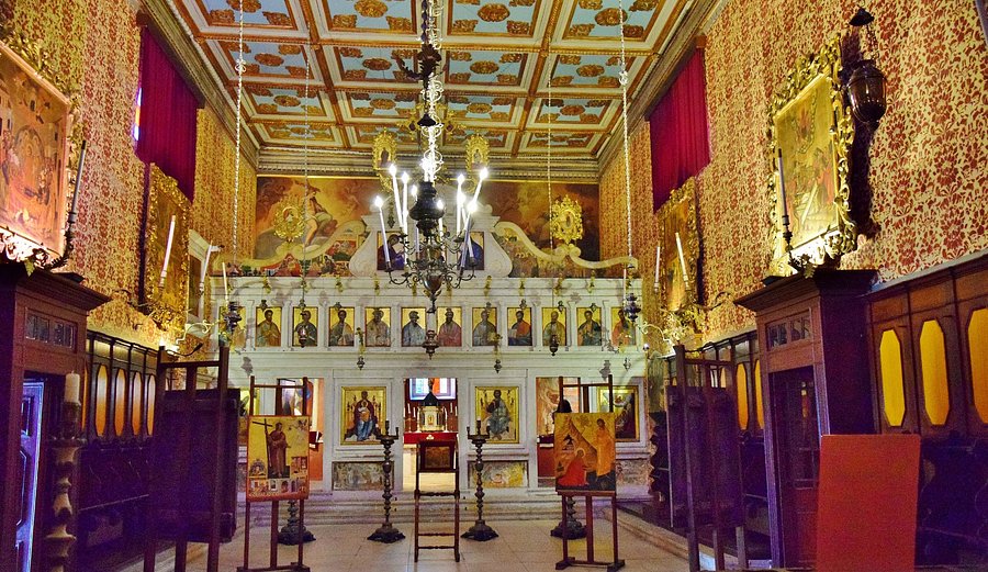Ornate church interior with chandeliers, altar icons, and intricate architectural details.