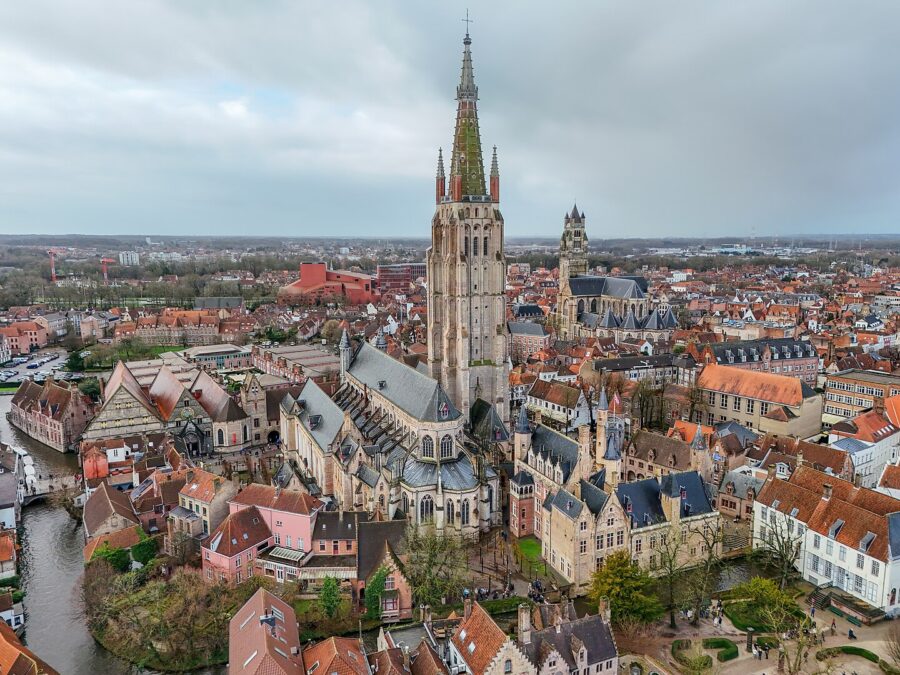 Aerial view of Bruges, Belgium, showcasing the Church of Our Lady amidst the city's historic architecture and canals.