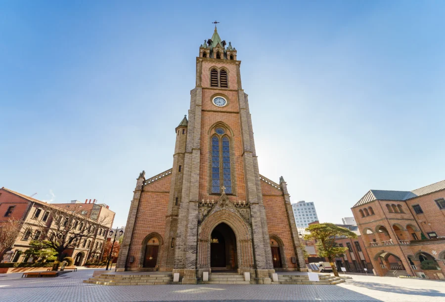 Gothic Romanesque church with brickwork, green spire, arches, stained glass, and clock.