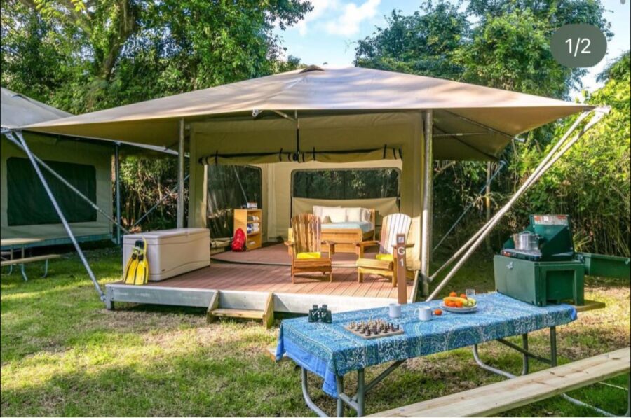 Tent with a table and chairs set on grass at Cinnamon Bay Campground, St. John, USVI.