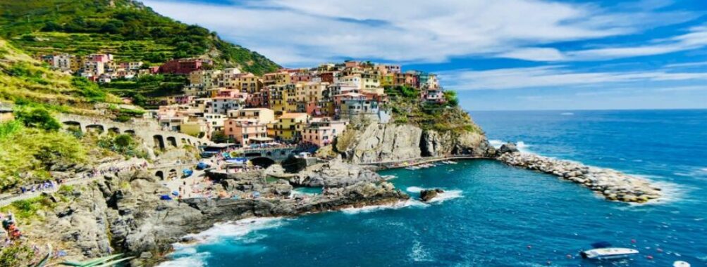 Picturesque Mediterranean village on a rocky cliff with vibrant sea and lush hills.