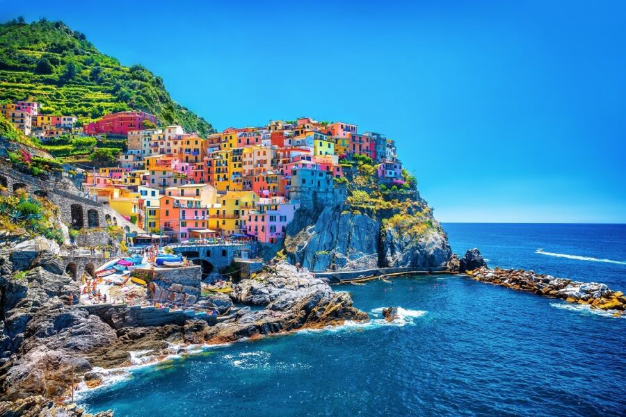Vibrant Cinque Terre village with colorful houses, azure sea, and lush vineyards.
