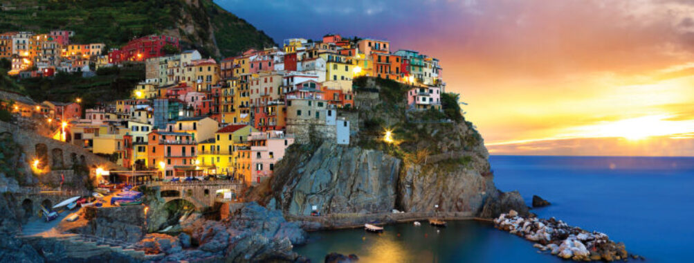 Sunset over Cinque Terre coastal village with colorful buildings and sea view.