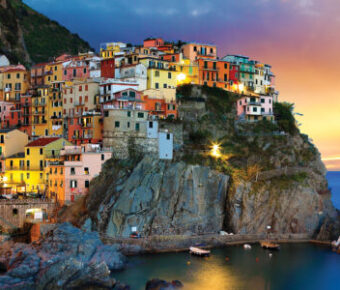 Sunset over Cinque Terre coastal village with colorful buildings and sea view.